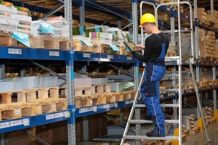Opérateur sur un escabeau devant des rayonnages de stockage